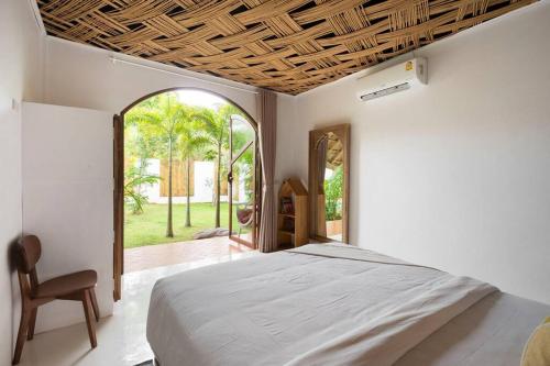 ein Schlafzimmer mit einem Bett, einem Stuhl und einem Fenster in der Unterkunft Aloe Ecological Boutique Villa 2 in Ao Nam Mao