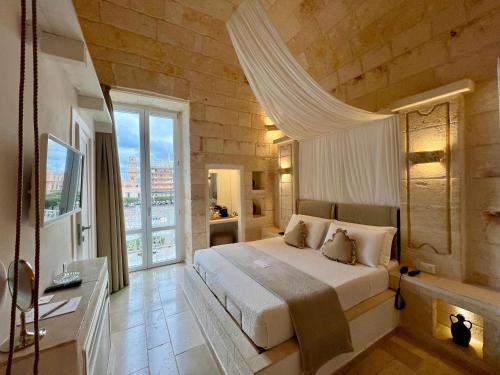 een slaapkamer met een groot bed en een groot raam bij Vittorio Emanuele Charming Suites in Monopoli