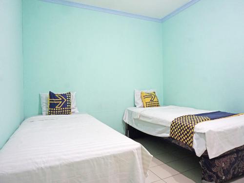 two beds in a room with blue walls at SPOT ON 91860 Amazon Homestay Syariah 2 in Sukabumi