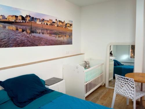 ein Schlafzimmer mit einem Bett, einem Tisch und einem Gemälde in der Unterkunft MYSaintAubin in Saint-Aubin-sur-Mer