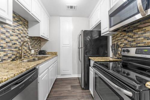 a kitchen with white cabinets and a stainless steel refrigerator at Family Friendly 2bdrm-Walk To At&t/Cowboys Stadium in Arlington