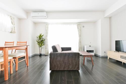 a living room with a couch and a table and a tv at Sun Court Hondori Garden Hills in Tsukisappu