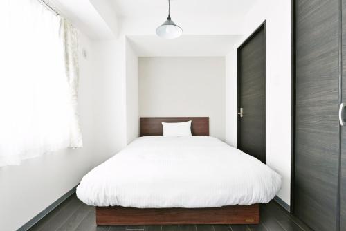a bedroom with a white bed and a black door at Sun Court Hondori Garden Hills in Tsukisappu