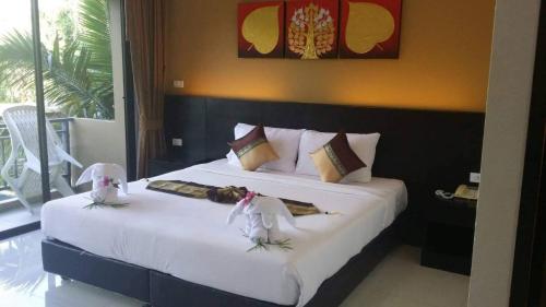 1 dormitorio con 1 cama grande con sábanas blancas en Naiyang Beach Hotel SHA Plus, en Nai Yang Beach