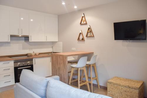 a kitchen with white cabinets and a blue couch at Fabuleux studio, belle décoration et excellent emplacement in Pas de la Casa