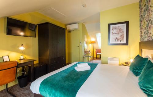 a bedroom with a large bed with a green blanket at Logis Hôtel Le Vert Galant in La Flèche