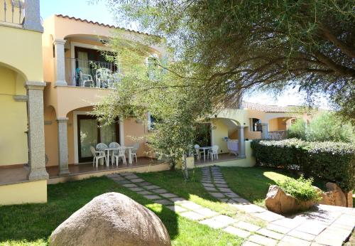 a house with a yard with a rock in front of it at Residence con piscina a Badesi, appartamenti con WIFI e A.C in Badesi