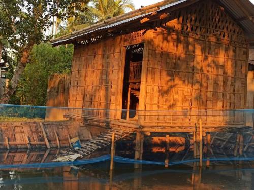 a small wooden building sitting in the water at Assam Villa - by Storyweavers Retreat in Jorhāt