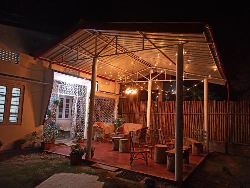 a pavilion with a table and chairs on a patio at night at Assam Villa - by Storyweavers Retreat in Jorhāt