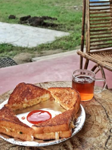 a plate with a sandwich and a glass of beer at Assam Villa - by Storyweavers Retreat in Jorhāt