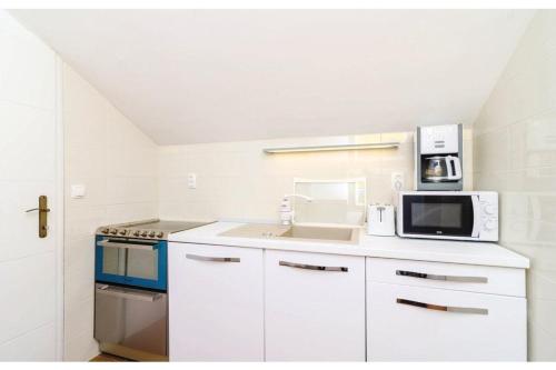 a white kitchen with a sink and a microwave at Villa Heart of Stone in Ploče