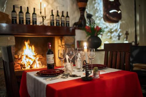 a table with wine glasses on a table with a fireplace at The Litchi Tree Amber Mountain Boutique Hotel in Ambohitra