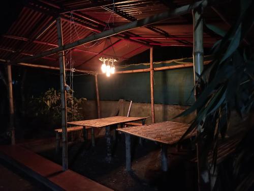 a dark room with two tables and a light at Assam Villa - by Storyweavers Retreat in Jorhāt