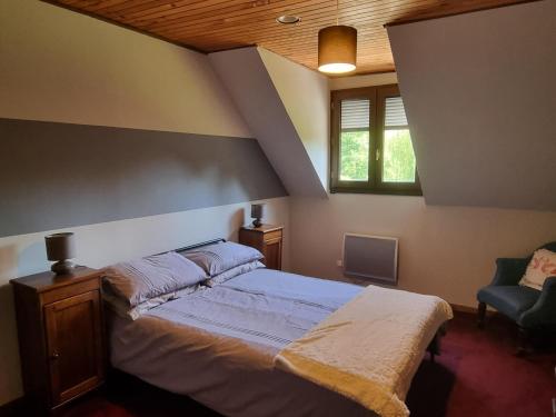 1 dormitorio con 1 cama grande y 1 silla en Firs Lake, en Ruillé-le-Gravelais