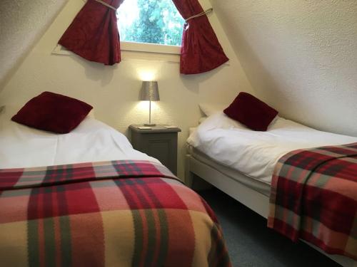 two beds in a small room with a window at Pebbles Seaside Lodge in Kent