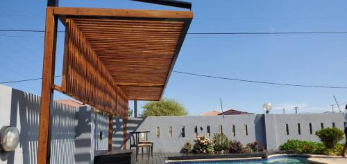 a wooden canopy over a patio with a swimming pool at LinT Guest House in Gaborone