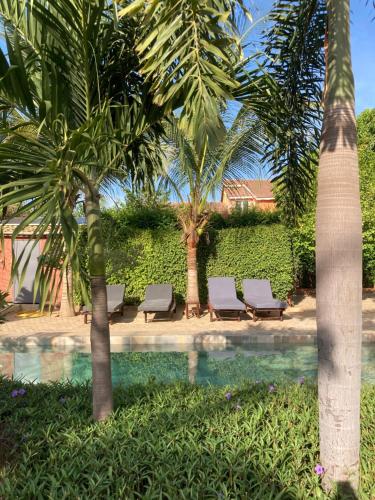 a swimming pool with lounge chairs and palm trees at Villa Aquarêve in Saly Portudal