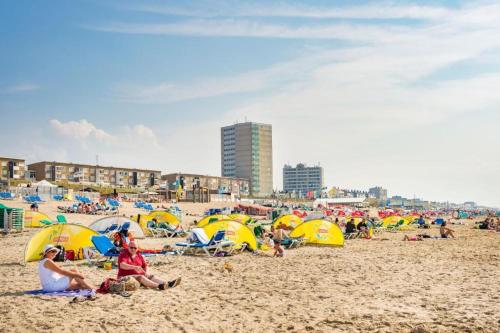 a group of people sitting on a beach with umbrellas at CHALET FOR 2 AT THE BEACH in Zandvoort