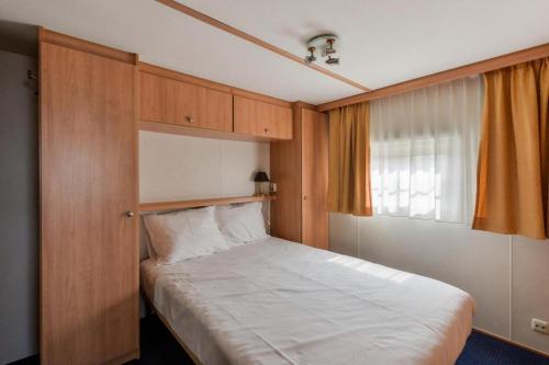 a small bedroom with a bed with a window at CHALET FOR 2 AT THE BEACH in Zandvoort