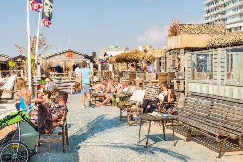 a group of people sitting on benches on a beach at CHALET FOR 2 AT THE BEACH in Zandvoort