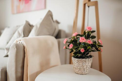 un jarrón de flores rosas sentado en una mesa en White Apartment en Liubliana