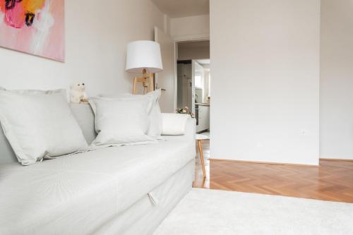 a white bedroom with a white bed and a mirror at White Apartment in Ljubljana
