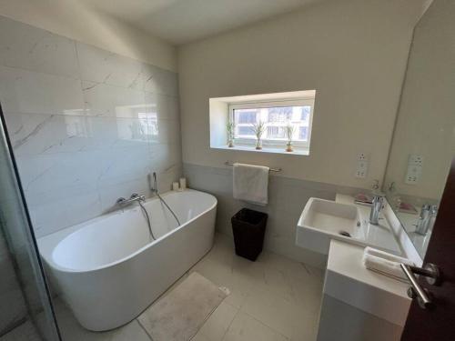 a white bathroom with a tub and a sink at Cinnamon Life - Luxury 2 Bedroom Apartment. in Colombo