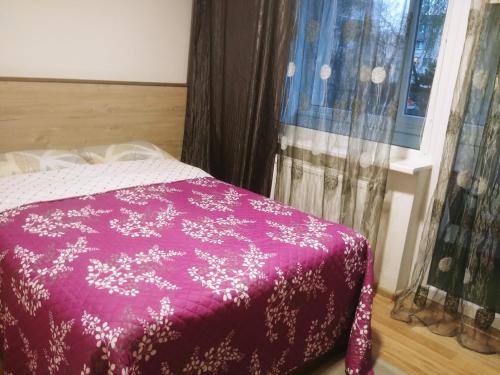 a bedroom with a purple bed with a window at Apartamentai Dana in Birštonas