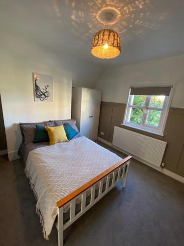 - une chambre avec un lit, une fenêtre et un lustre dans l'établissement Stylish 2 bedroom cottage, close to town centre, à Worthing