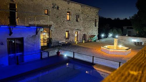 a swimming pool in front of a building at night at Tour de charme atypique in Beauregard-lʼÉvêque