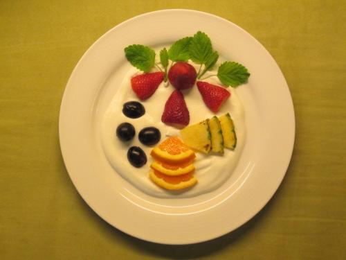 a white plate with fruit and whipped cream on it at Hotel Schick in Bad Wörishofen