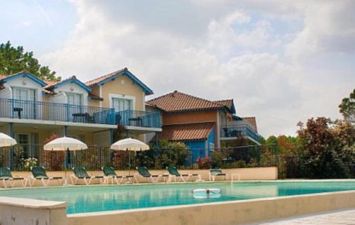 una casa con piscina con sedie e ombrelloni di Le Hameau du lac a Marciac