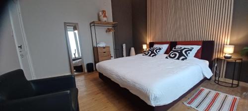a bedroom with a bed with pillows and a chair at De galerie - dessert coulors in Ypres