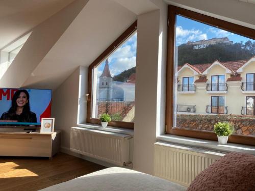 a bedroom with a large window and a tv at ApartamentS in Râşnov