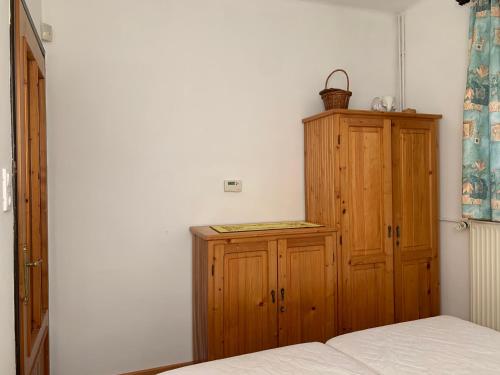 a bedroom with a wooden cabinet and a bed at Bolla Nyaralóház in Hegyhátszentjakab