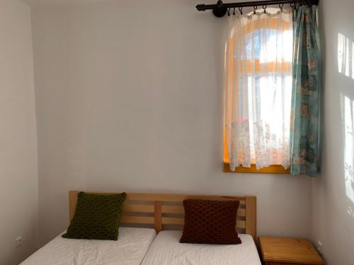 a bed in a room with a window and a bed with pillows at Bolla Nyaralóház in Hegyhátszentjakab