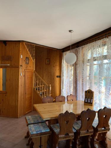 a dining room with a wooden table and chairs at Bolla Nyaralóház in Hegyhátszentjakab