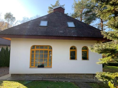 a white house with a black roof and windows at Bolla Nyaralóház in Hegyhátszentjakab