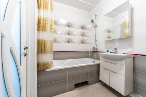 ein Badezimmer mit einer Badewanne, einem Waschbecken und einem Spiegel in der Unterkunft Апартаменты метро Вырлица in Kiew