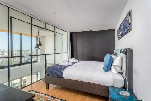 a bedroom with a large bed and glass walls at Super artist's apartment with parking in Tel Aviv