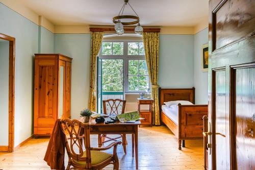a bedroom with a table and a bed and a window at Hotel Lago di Braies in Braies