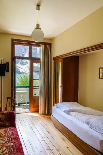 a bedroom with a bed and a large window at Hotel Lago di Braies in Braies