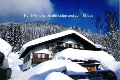 a house covered in snow with trees in the background at Haus Christl in Reit im Winkl