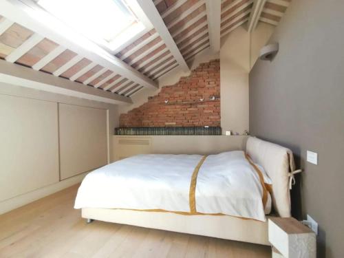 a bedroom with a white bed and a brick wall at CasaDei Sweet Home Design & Relax - Beach Parking in Cervia