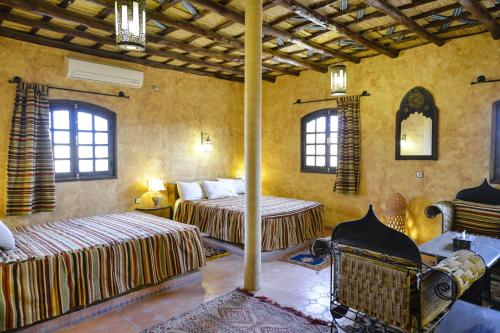 a bedroom with two beds and a fireplace at Riad Nezha in Merzouga