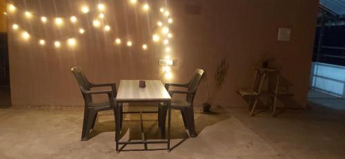 a table and two chairs with lights on the wall at M Cube Service Apartments in Sakleshpur