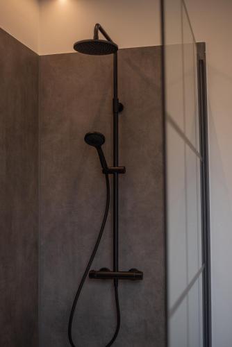 a shower with a black shower head in a bathroom at Domein Den Buiten Bed And Breakfast DnD in Sint-Niklaas