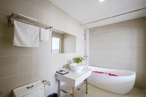 a bathroom with a white tub and a sink at The May Phu Quoc Hotel in Phu Quoc