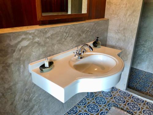 La salle de bains est pourvue d'un lavabo blanc et d'un miroir. dans l'établissement Ma Maison Khaoyai, à Ban Sap Bon