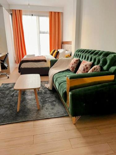 a living room with a green couch and a bed at Avana studio in Nairobi
